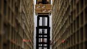 Photograph of worker between two enormously high stacked bookshelves at the Harvard Depository