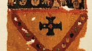 A colorful Byzantine funerary tunic fragment depicts faces and vegetal patterns with a border of gemstones.
