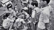 Black and white photo of a group of Vietnamese children, titled “Schoolchildren Playing Cards”