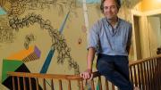 Dan Chiasson at home in front of a “sometimes delightful, sometimes disturbing” mural by David Teng Olsen, which appears in The Math Campers.