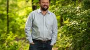Ross Douthat standing in a wooded park