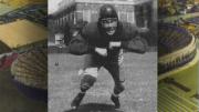 Football player Chubb Peabody, in pads and helmet, charges forward.