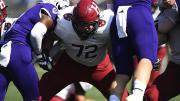 A Harvard lineman holds back two Holy Cross defenders