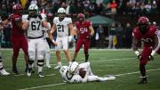 Truman Jones celebrates a tackle with Derek Kyler lying on the ground beside him.