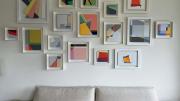 A collection of abstract geometric paintings hang above a white couch