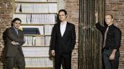 Editors with their product. Left to right, Keith Gessen, Mark Greif, and Chad Harbach of <i>n+1</i> at their Brooklyn office, with a bookcase full of past issues.
