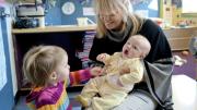 Mary Kinsella Scannell, vice president for early education and care, plays with baby Kinsey Ferraguto and toddler Margot Vorhees.