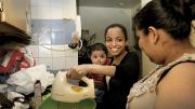 Katty Morocho (center), a social worker for Little Sisters, teaches client Zenaida Vega to bake a cake while Vega’s nephew, Miguel, looks on. Vega hopes to find work at a bakery.