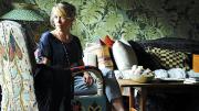 Anna Laurent backed by wallpaper showing split-leaf philodendron (<i>Monstera deliciosa</i>)