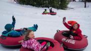 Kids in snow suits having fun snow-tubing 