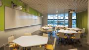 One of various flexible classrooms, filled with white hexagonal tables and bright yellow chairs