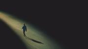 Drawing of a distant solitary figure walking alone toward the horizon along a narrowing path of light edged on both sides by darkness