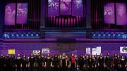 Children singers performing on stage with purple lighting 