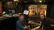 Finn Bamber and Clay Oxford sit beside a sound board with a theater set behind them