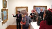 Docent Susan Glassman describes a painting to a group of guests