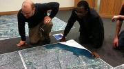 At the Center for Geographic Analysis office, the Harvard-MIT Data Center's Eric Alderman examines a map of Port-au-Prince with Jean-Lucien Ligonde, a businessman in the Boston Haitian community, in preparation for sending the map to Haiti to be used in relief work.