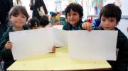 Children in a UBC classroom display a writing exercise on which they've been working. 