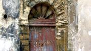 Note the intact Roman keystone and distinctively Portuguese spoke-wheel woodwork in this weathered door in Essaouira, Morocco (2006).