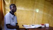 Physician Joshua Mukhama in the space where he conducts counseling: a gazebo with a sheet hung to separate the counseling area from the waiting area
