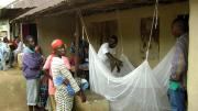 In Nganyahun village, a Red Cross volunteer and a community leader who work with GMin teach residents how to put up bed nets.