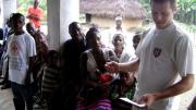 Using notes to bolster his command of Mende, the local language, Sam Slaughter ’09 introduces himself and the GMin team to villagers.