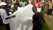 David Sengeh (under net) acts out his part in a skit on malaria, as two Red Cross volunteers hold the net. The skit was narrated in Mende by Red Cross volunteers.