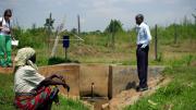 At a water collection site near Busia, Kenya, Leonard Bukeke, rural water project coordinator for IPA, shows the author around and introduces her to Seline Luyemba (foreground), the local resident who is responsible for making sure the dispenser gets refilled when it's near empty.
