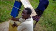 At another collection site near Busia, Loice Pamba adds chlorine before filling her water jug.