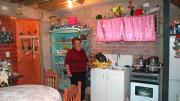 Rosa Estrella Ortega Roa stands in the kitchen of her home in the ELEMENTAL development in Santiago's Renca neighborhood. She moved in just a few months ago, and plans to finish the walls and ceiling. Ortega says even with unfinished walls and plywood overhead, this is a big improvement over her former home in the campamento, which had a muddy dirt floor.