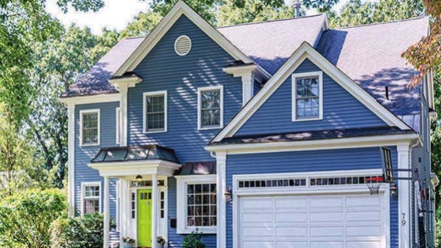 Exterior of blue house with garage surrounded by greenery