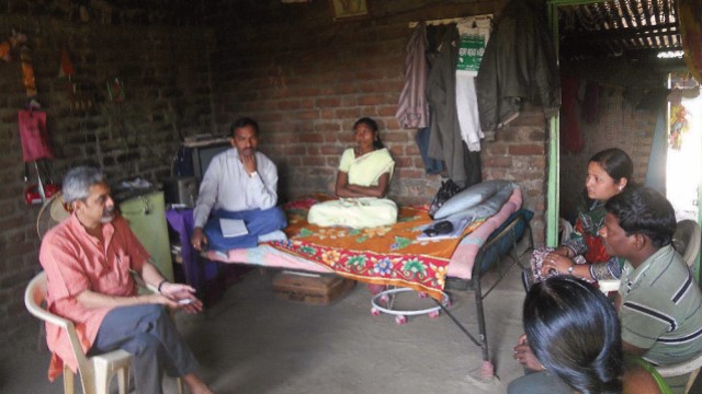 Photograph of Vikram Patel visiting with family members of a farmer in Maharashtra, India, who committed suicide