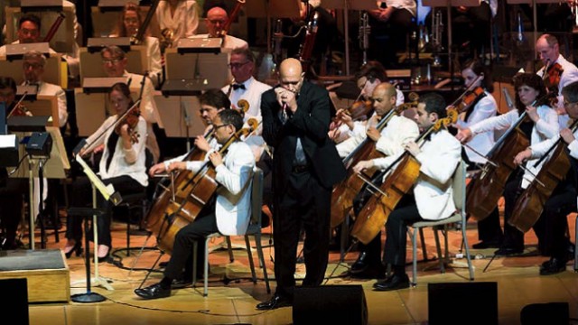 Johnson plays his harmonica with the Boston Pops orchestra behind him.