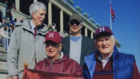 Alumnus Paul Lee ’46 carries the (replica) Little Red Flag at the 2012 Harvard-Yale game. Steve Goodhue ’51 is beside him; Spencer Ervin ’54 and Jeff Lee ’74 stand behind.
