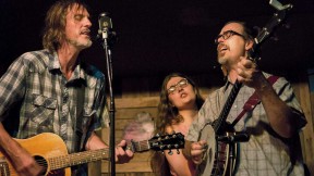 A bluegrass guitarist, banjoist, and singer perform on stage
