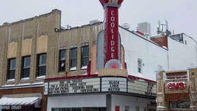 Photo of the exterior of Coolidge Corner Theater, with its vertical red neon sign.