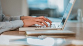 Hands typing on a computer keyboard.
