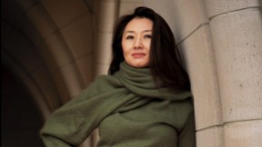 Portrait of Jeannie Suk Gersen, an elegantly dressed Korean American woman leaning against a stone archway.