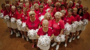 Photo of a cheerleader group composed of elderly women, all in red tops and white skirts, with pompoms