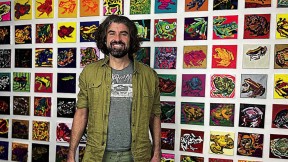 Bradley Scott Davis standing in front of a wall of frog paintings