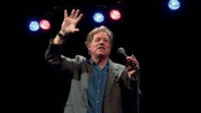 Jimmy Tingle holding a microphone and performing on stage 