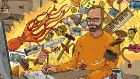 A professor sits at a computer whose screen is shooting out a beam of light filled with all sorts of animals and musical instruments