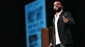 With a front page from <i>The Onion</i> projected in the background, Thurston emcees the 2009 SXSW Interactive Web Awards.