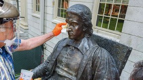 Conservators from Skylight Studios work on the John Harvard statue