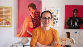 David Andersson standing among his colorful painted portraits