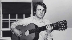 Photograph of William Randall playing guitar in his Lowell House room, c. 1970-1971