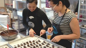 In the Sôcôla kitchen, sisters Wendy (left) and Susan Lieu dip a few dozen chocolate truffles laid out on baking parchment. 