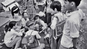 Black and white photo of a group of Vietnamese children, titled “Schoolchildren Playing Cards”