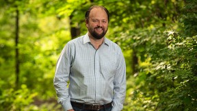 Ross Douthat standing in a wooded park