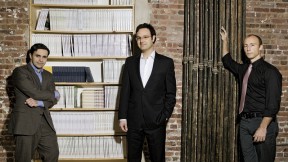 Editors with their product. Left to right, Keith Gessen, Mark Greif, and Chad Harbach of <i>n+1</i> at their Brooklyn office, with a bookcase full of past issues.
