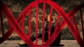 A double-helix image, in red, framing a man in military camouflage, crouched, seated, holding his head, and